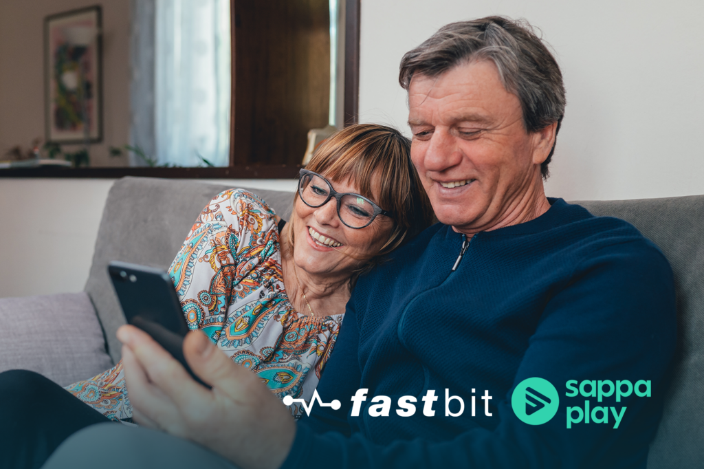 Två personer sitter i en soffa och tittar på en mobiltelefon.